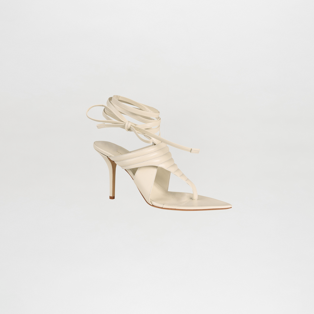 White strappy high-heeled shoe on a light gray background