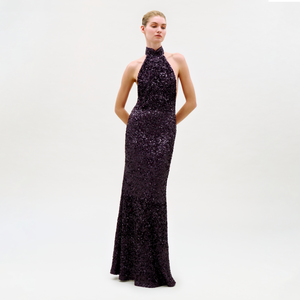 Woman wearing a dark purple sequin gown on a white background