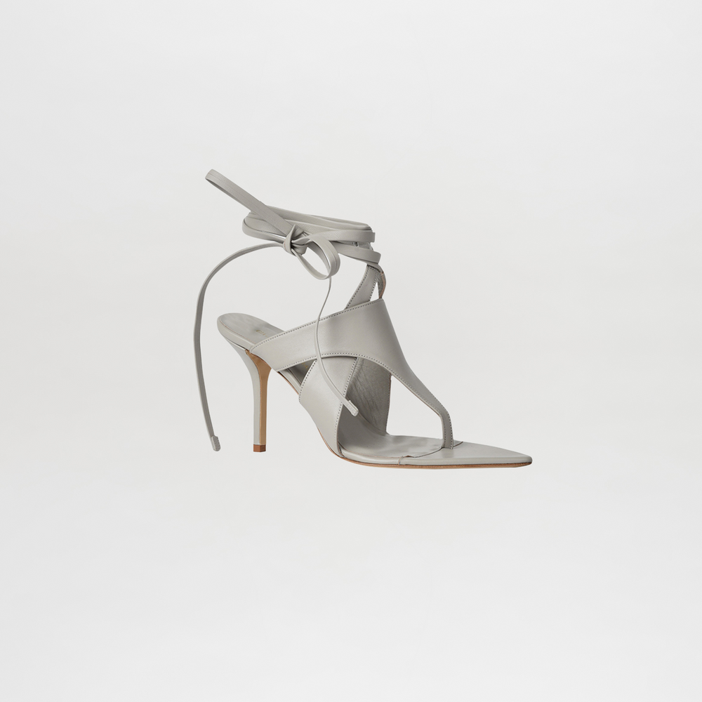White high-heeled sandal with thin straps on a light gray background