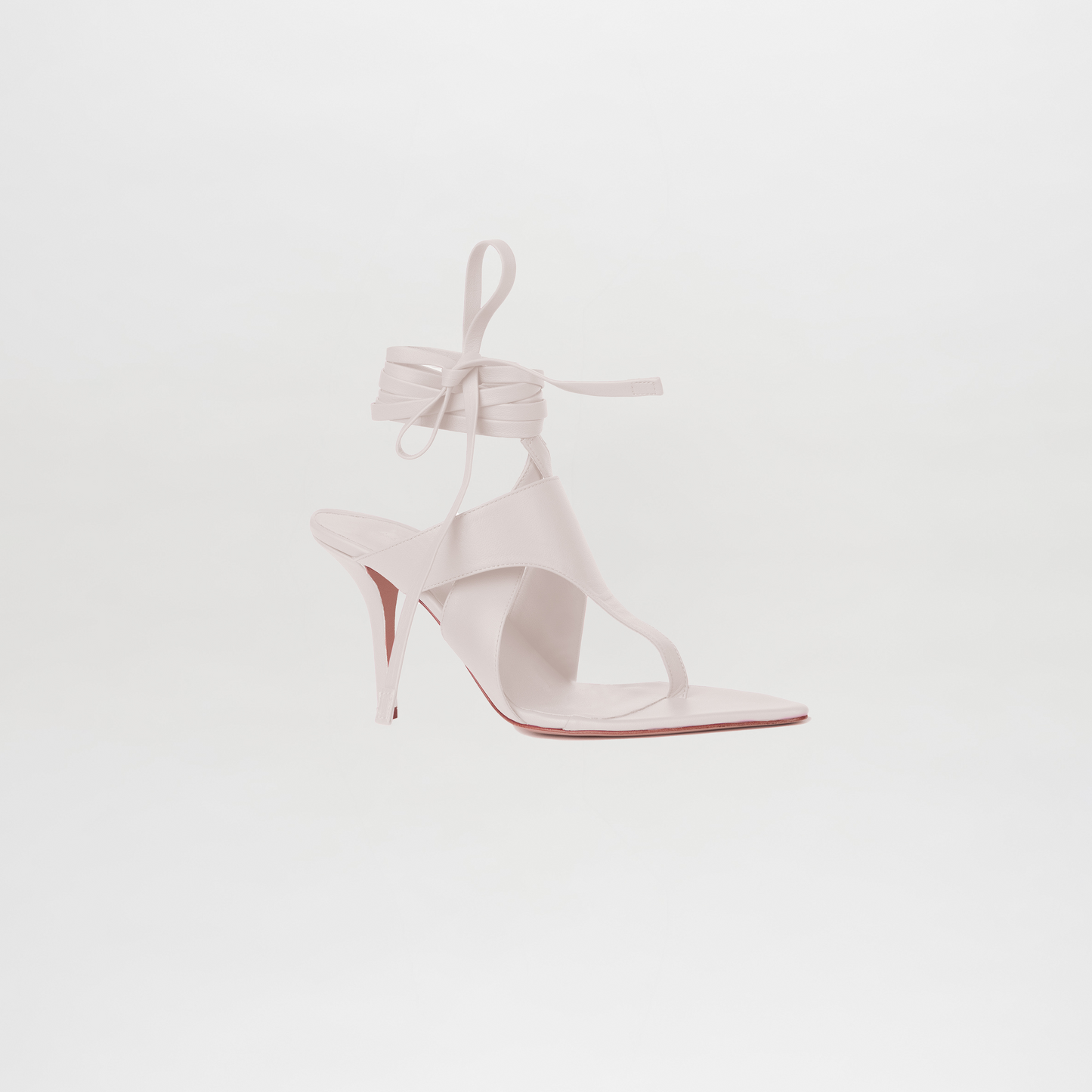 White high-heeled shoe with a red sole on a light gray background