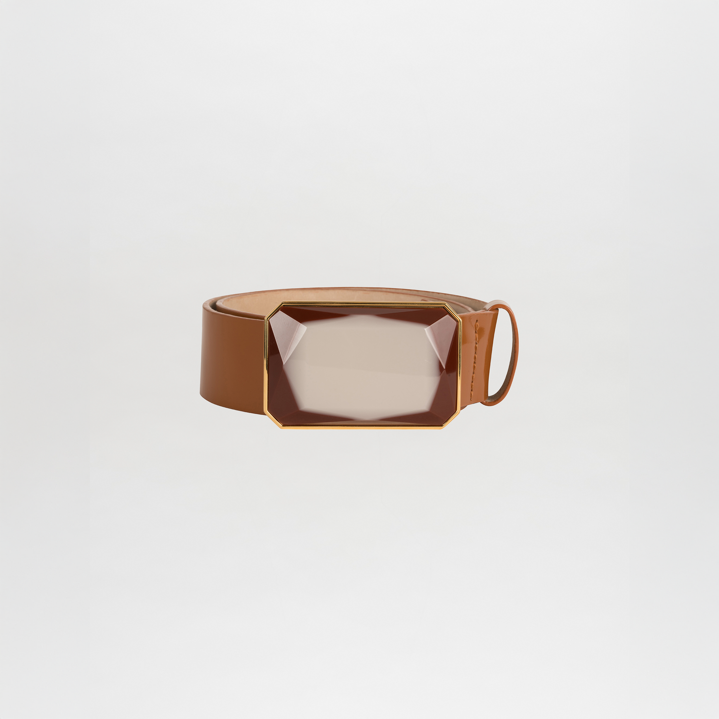 The Dora Belt is a brown leather belt with a large geometric translucent buckle featuring gold accents, shown on a plain white background.
