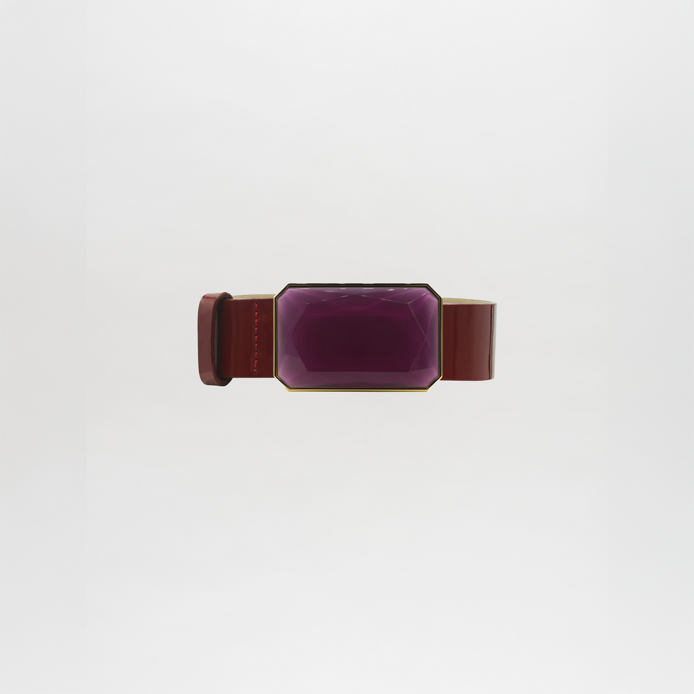 The Dora Belt features a wide brown band with a large, faceted rectangular purple gem at the center. Please allow standard processing and shipping time for delivery. Shown against a plain white background.