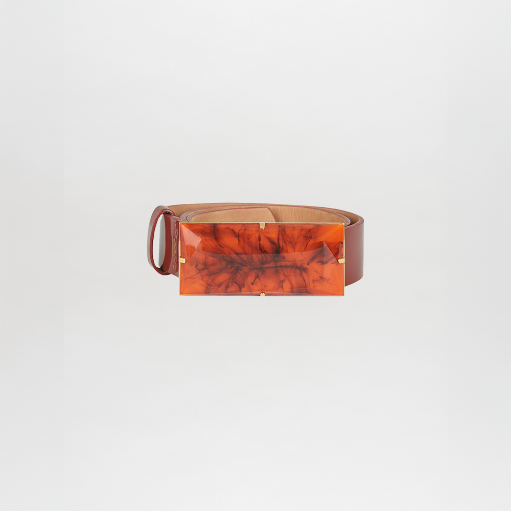 The Dora Belt Brick is a brown leather statement belt with a large, rectangular, marbled orange buckle, set against a plain white background.