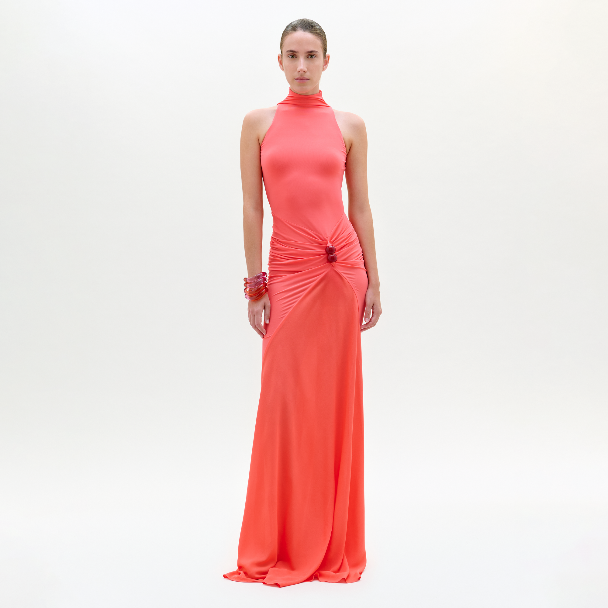 Woman wearing a coral evening gown on a white background