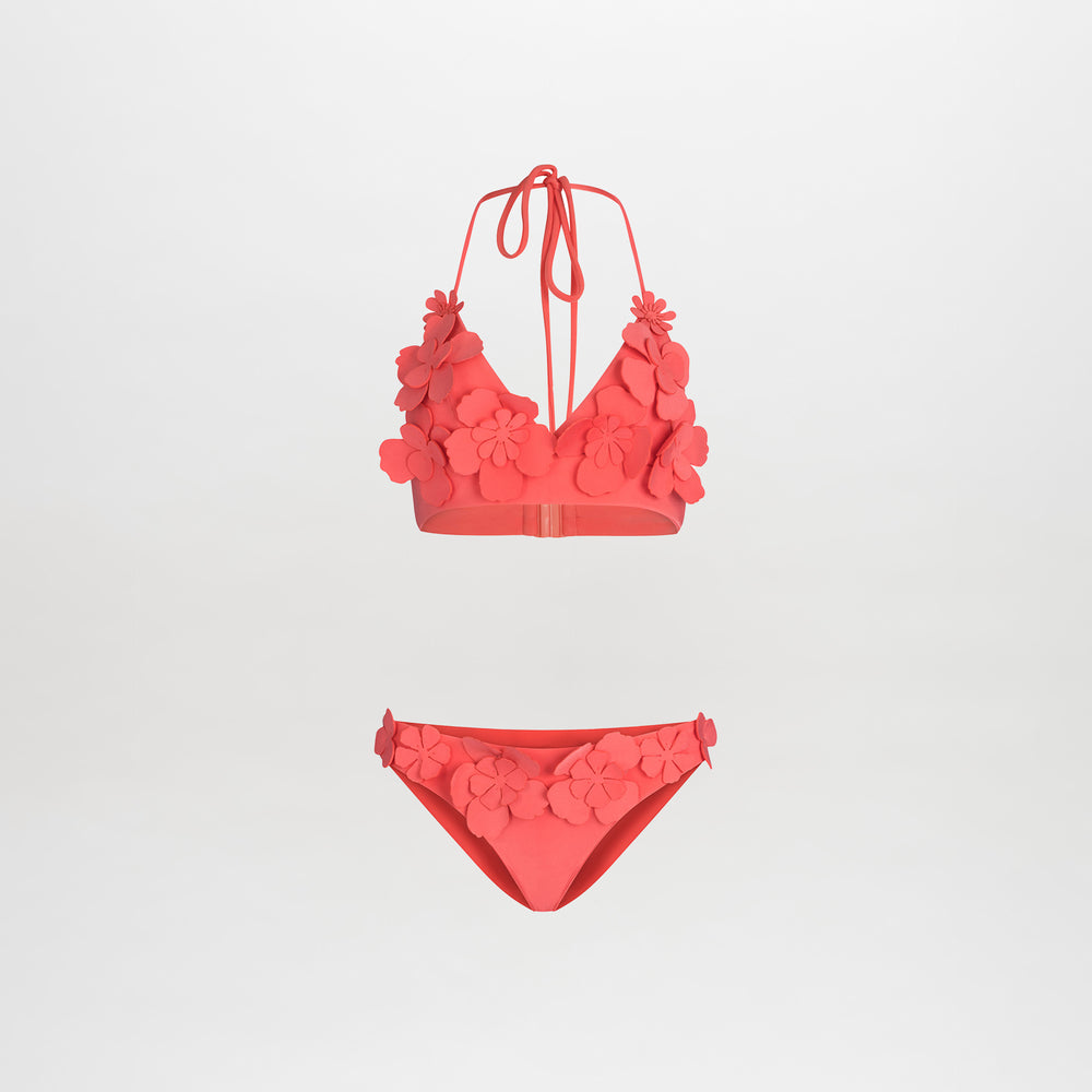 The Felisa Top + Fermina Bikini is a vibrant pink set featuring 3D floral details on the halter V-neckline top and side bottoms, showcased against a plain white background.