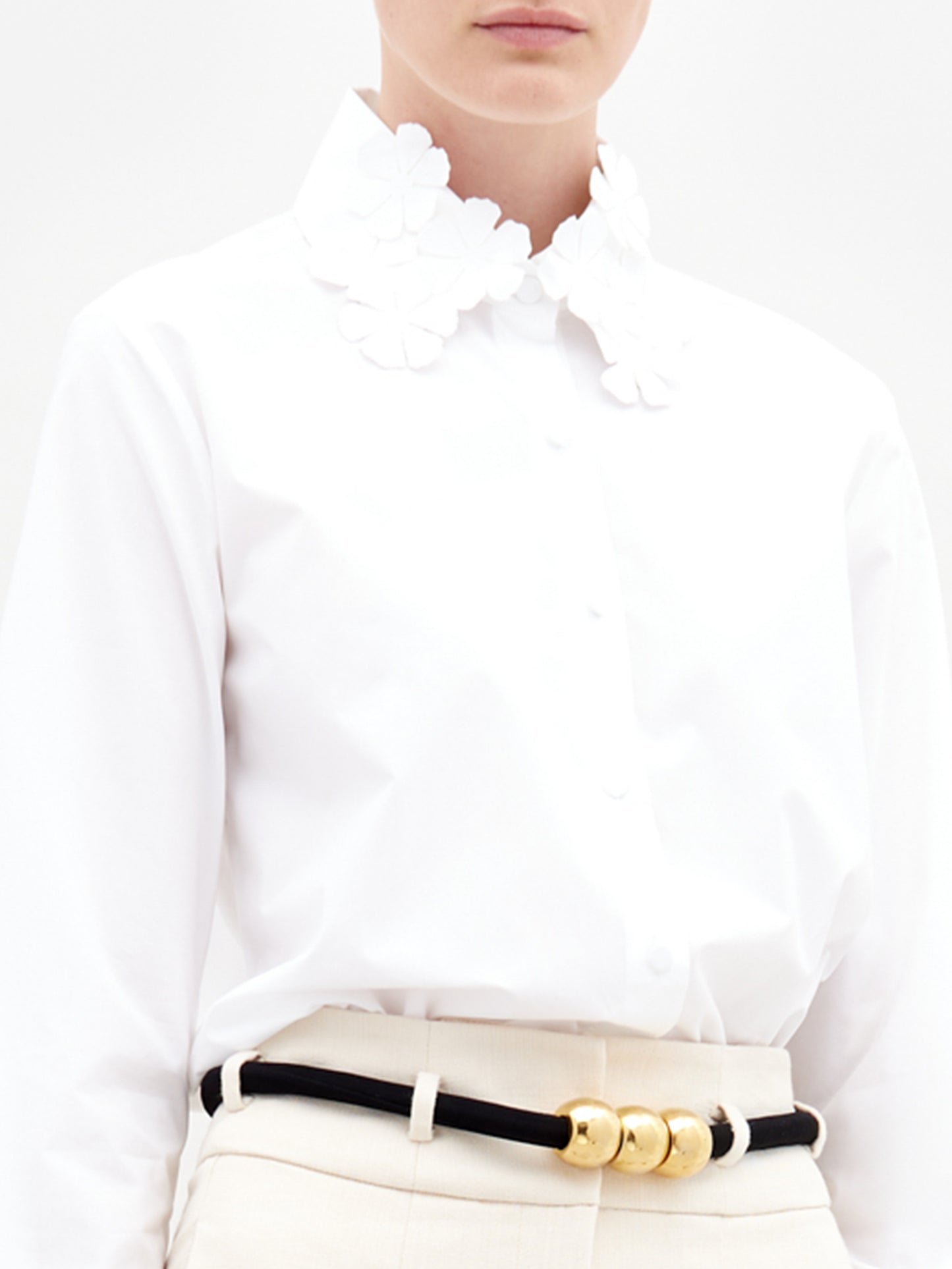A person wearing the Flower Blouse  in color White with a golden belt on a white background.