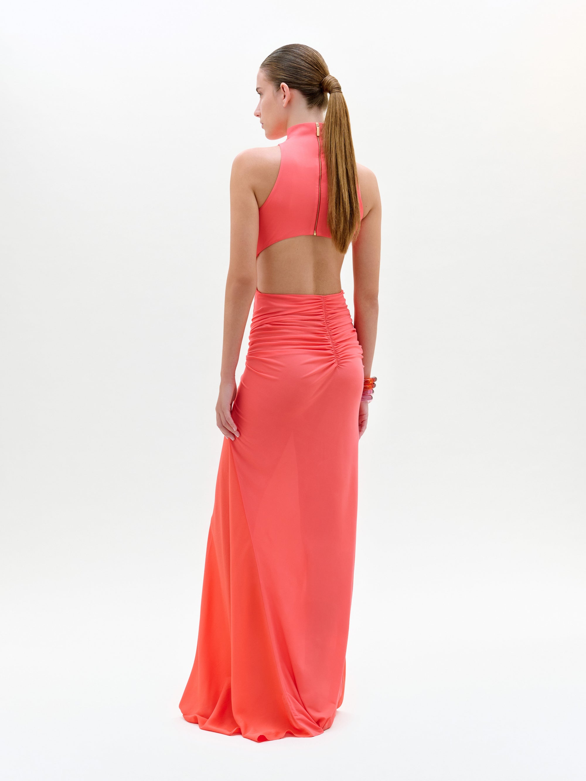 Woman wearing a coral halter neck gown on a white background