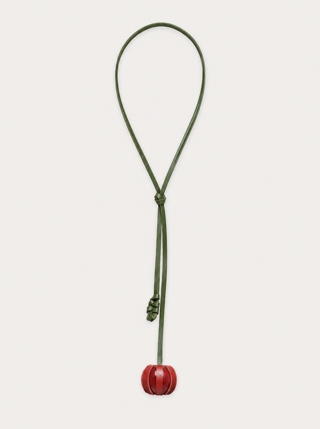 The Fruit Necklace features a green leather cord with a small red spherical pendant. A loose knot sits above the pendant, and the necklace is displayed on a white background.