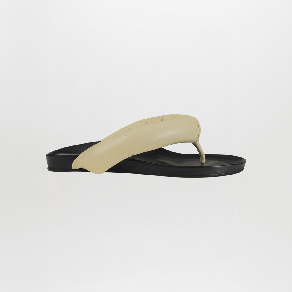 The Giacomo Sandal Ivory features a single flat design with a black sole and a thick, ivory puffy leather strap, shown against a plain white background.
