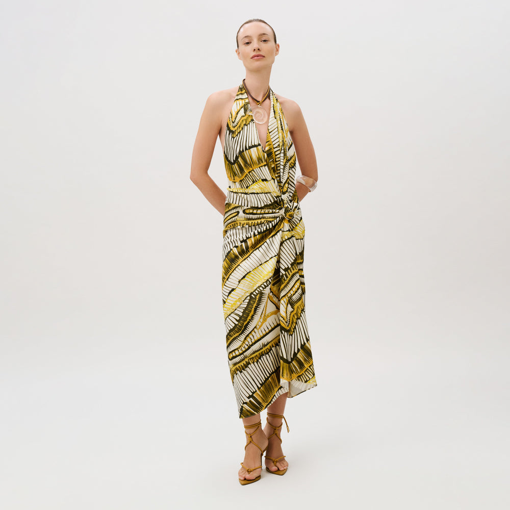 A model wears the Guadalupe Dress, a yellow and black patterned crepe satin midi dress with a front knot detail and lace-up heels.