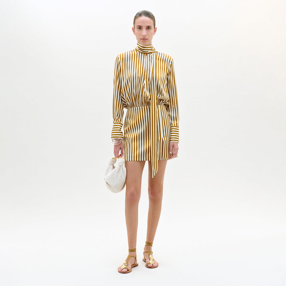 Woman wearing a gold and white striped dress on a white background