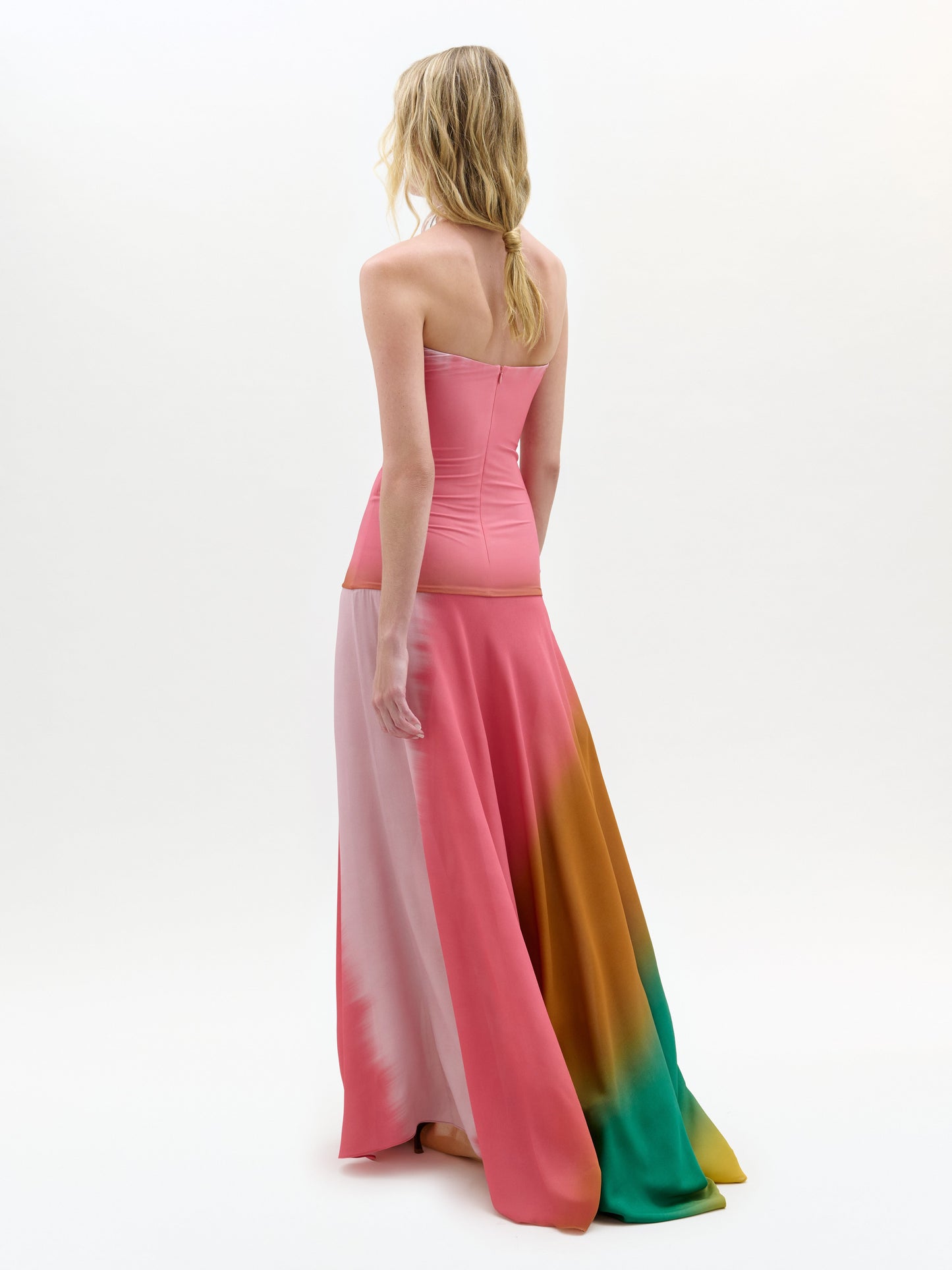 Woman wearing a strapless, long, multicolored dress on a white background