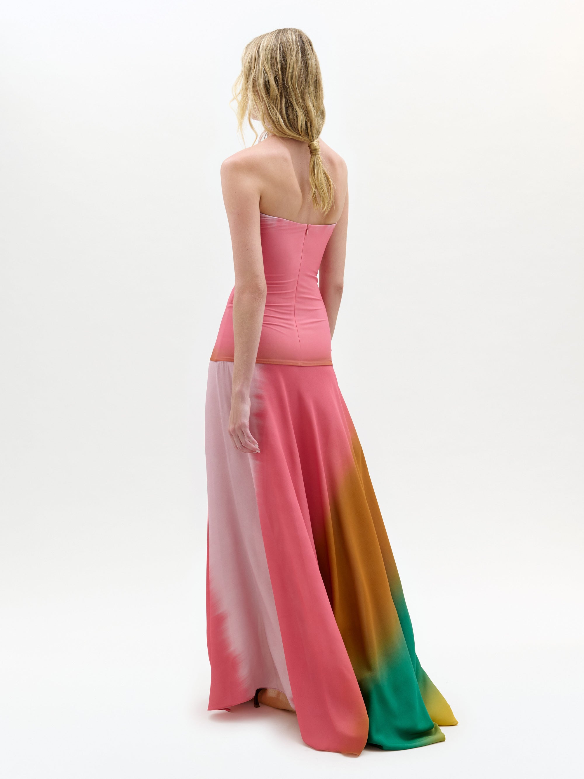 Woman wearing a strapless, long, multicolored dress on a white background