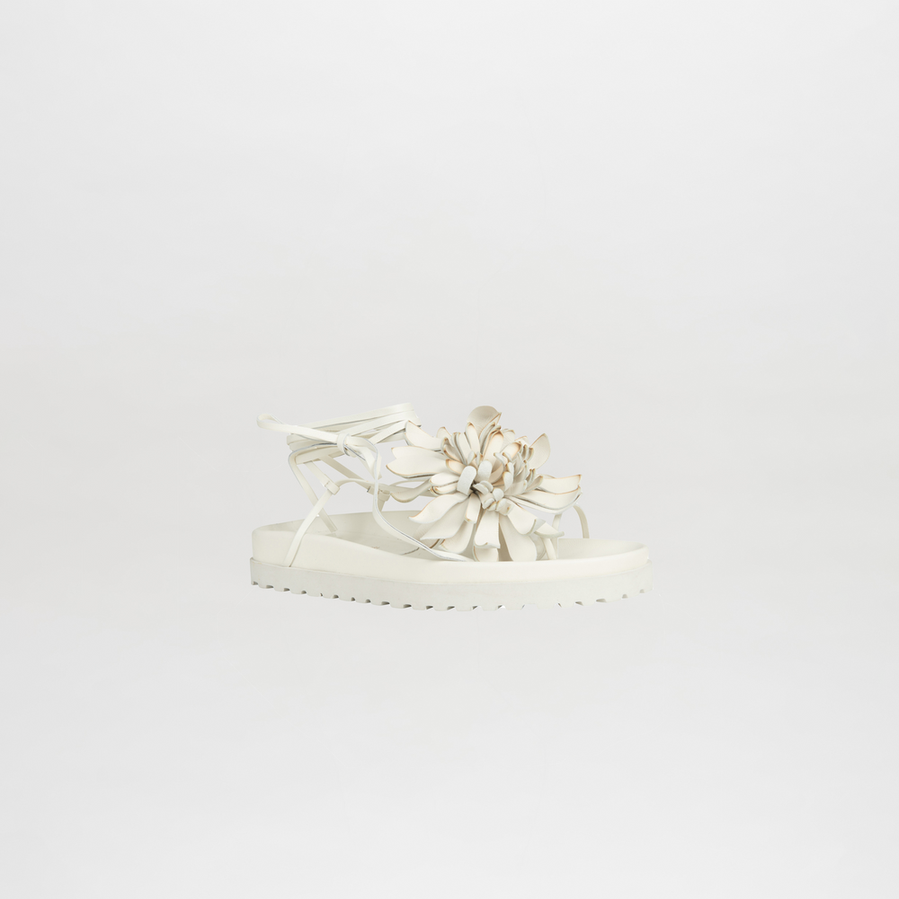 White sandal with floral design on a light gray background
