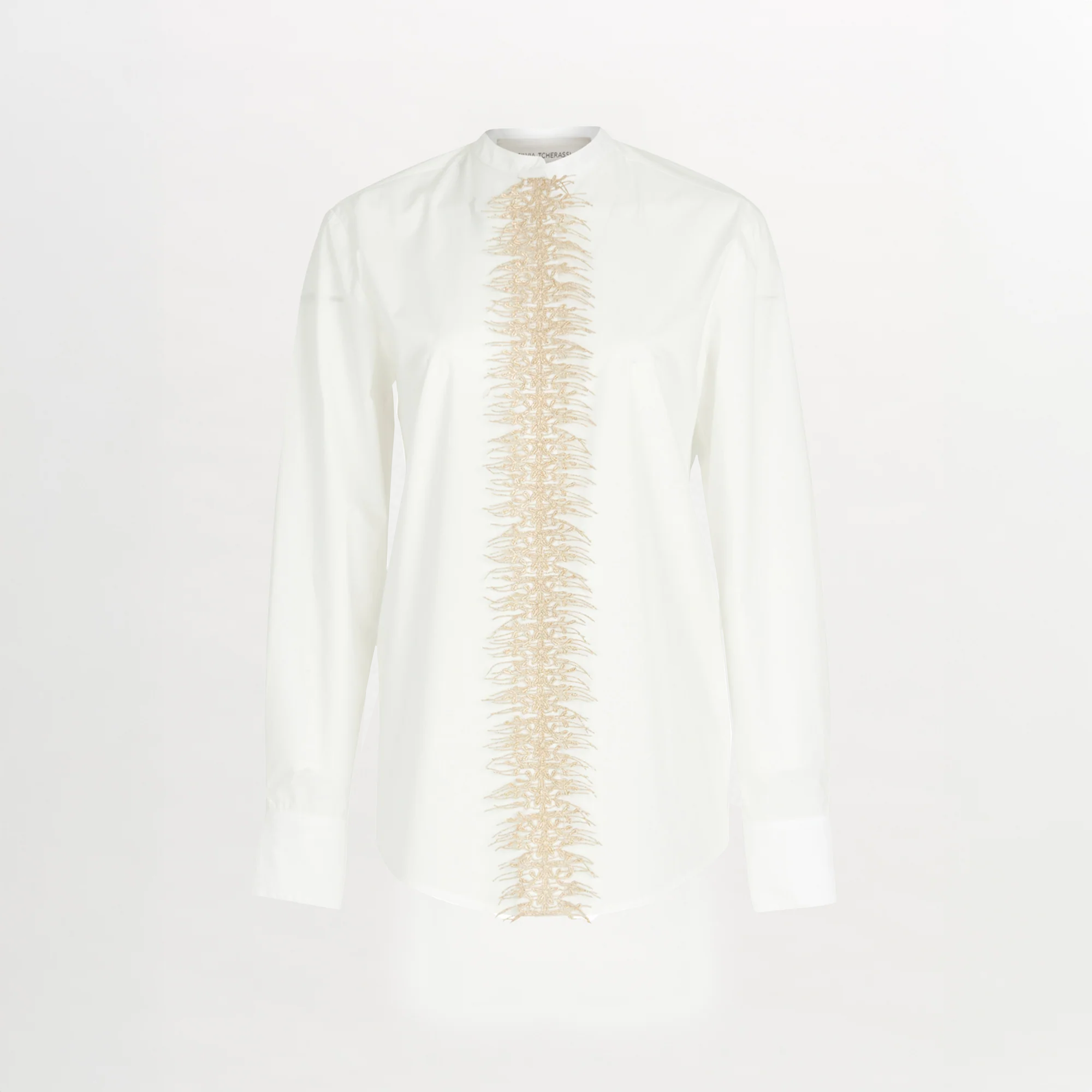The Isabel Blouse White is a cotton poplin button-up with a beige embroidered vertical design down the center front.