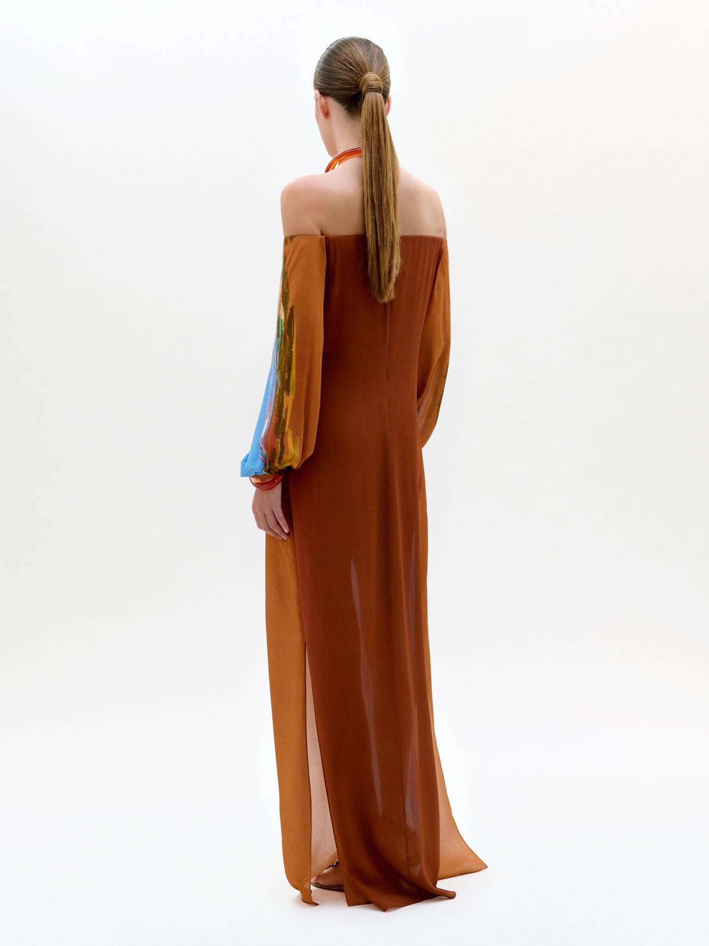 Woman wearing a long, off-shoulder dress with colorful sleeves on a white background