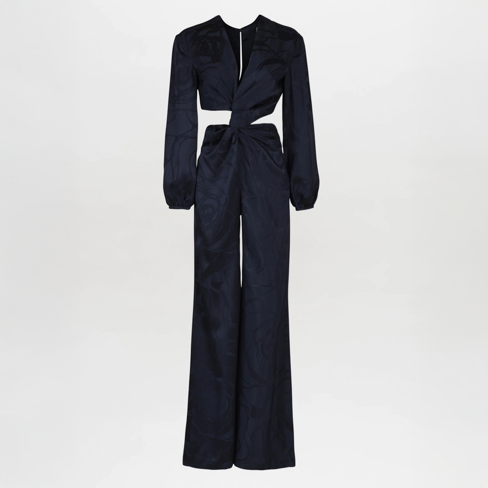 The Joely Jumpsuit Navy Jacquard, a black long-sleeve piece from the Resort 2023 collection, features a twisted front design, cutout at the waist, and wide-leg trousers.
