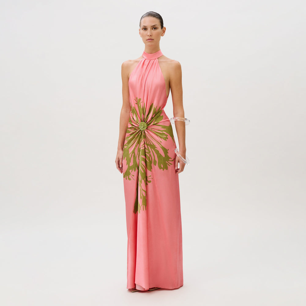 The Koori Dress is a floor-length pink silk halter dress featuring a green floral-like print gathered at the center waist.