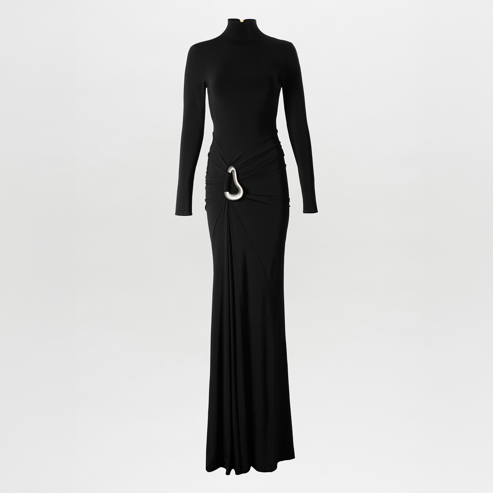 A woman poses against a plain white background wearing the Lena Dress, a long black maxi featuring a high neckline, open back, gathered waist, draped skirt, and white decorative detail at the hip.