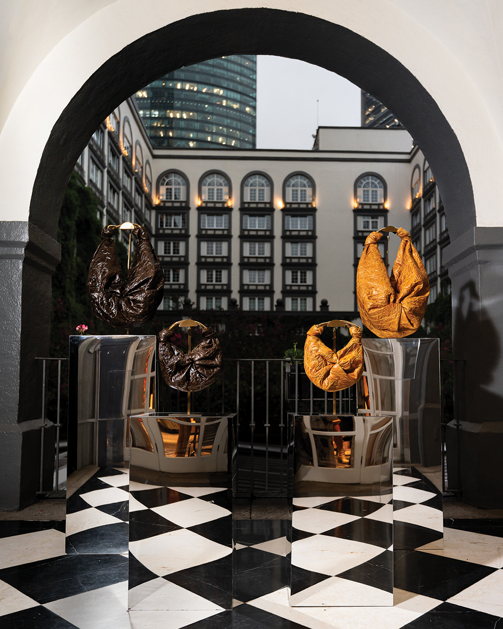 Gold and black leather handbags displayed in a stylish setting with a building in the background.