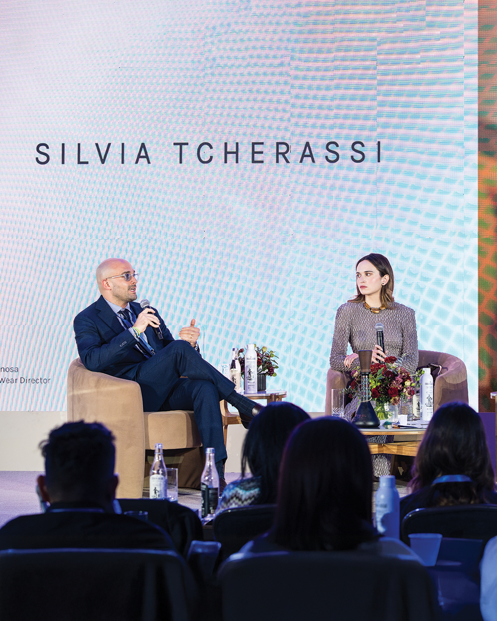 Two individuals on a stage with 'Silvia Tcherassi' displayed on a screen.