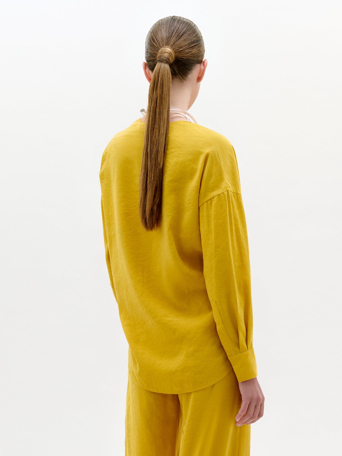 Person wearing a yellow outfit with a plain background