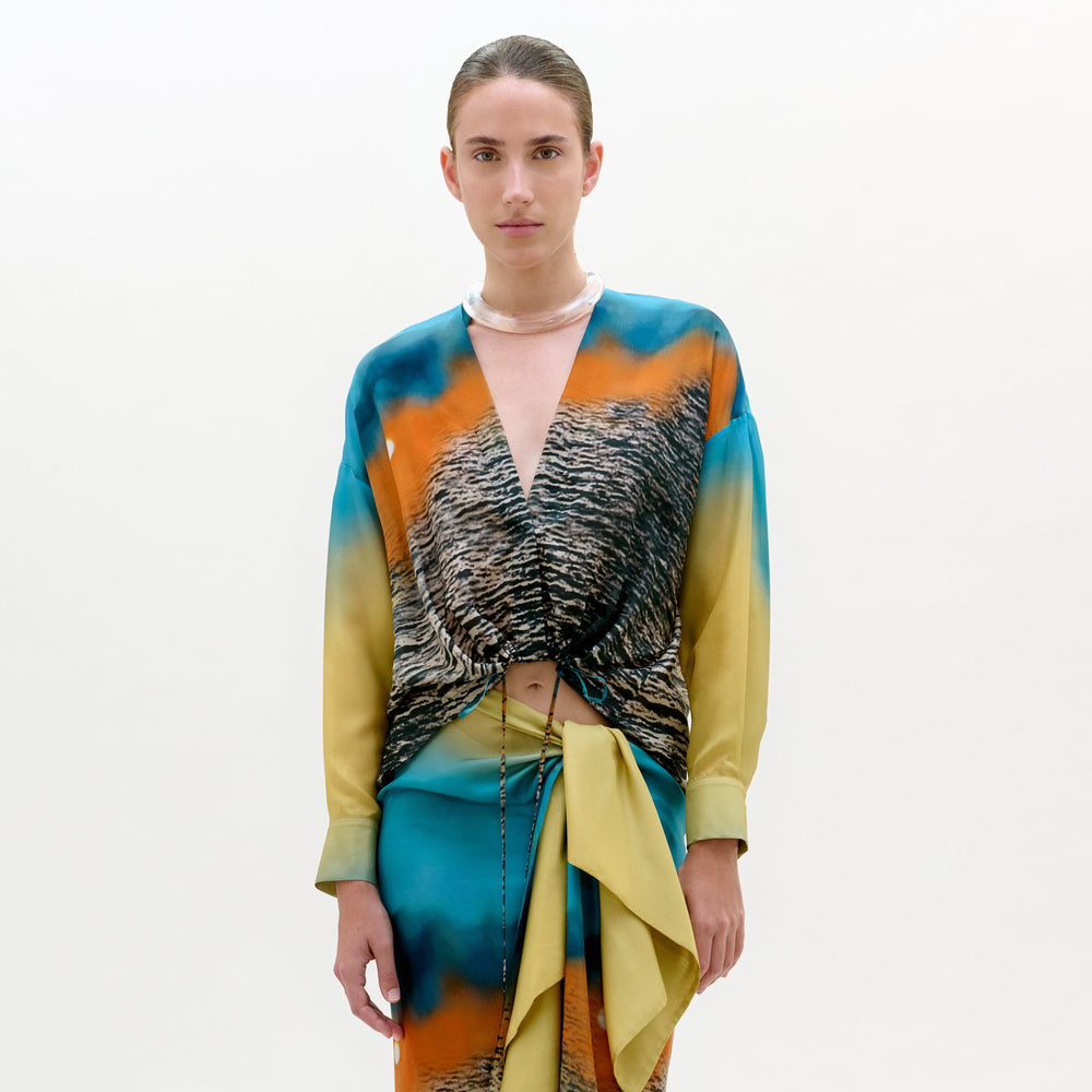 Model wearing a colorful outfit with a patterned top and skirt on a white background