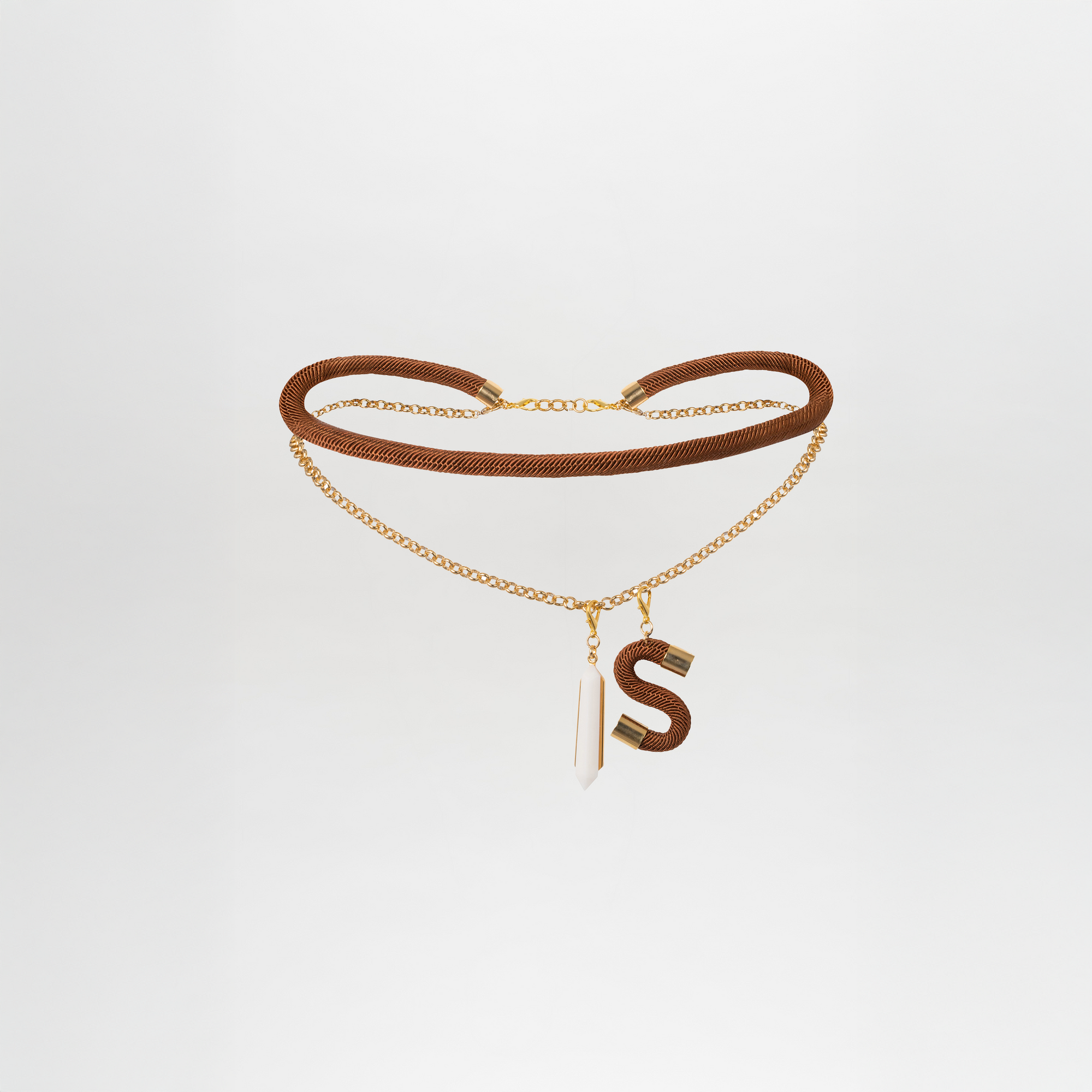 The Mireya Belt is a gold-plated brass choker with two layers—a thick mesh chain and a thin chain—adorned with a geometric crystal pendant and a large S charm. Shown against a plain white background.