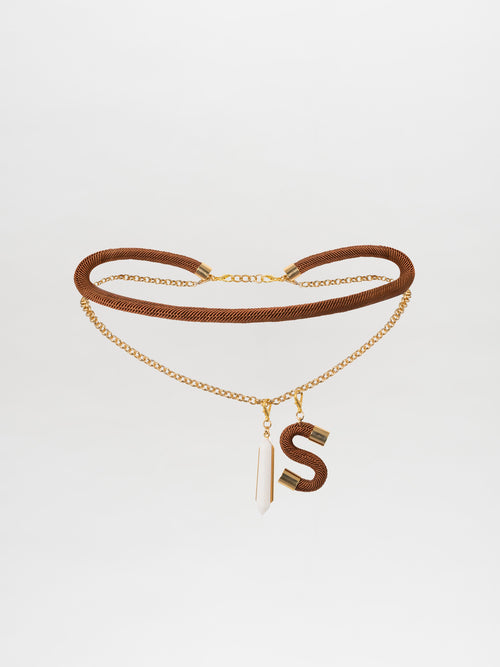 The Mireya Belt Ochre, featuring a double chain in brown and gold with a geometric crystal pendant and an "S" charm, crafted in a Tcherassi design, is showcased on a plain white background.