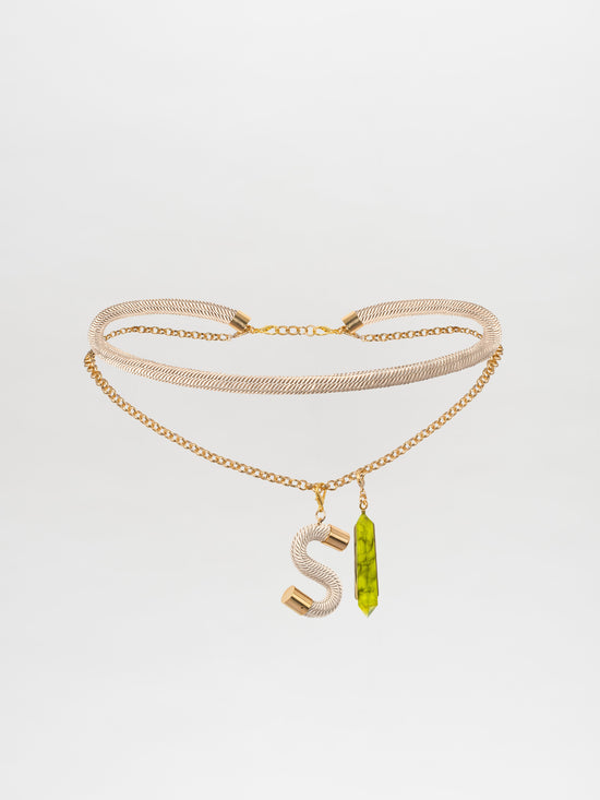 The Mireya Belt Pearl features a gold plated brass double-chain necklace adorned with an "S" pendant and a green crystal pendant, beautifully complemented by the metallic detailing on the lower chain.