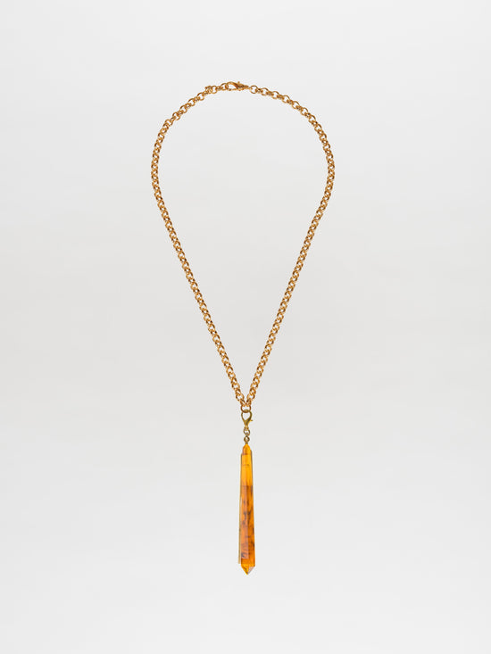 Introducing the Montse Necklace Amber: a stunning gold-plated brass chain with a long, narrow amber pendant that adds an elegant touch to any outfit. Perfect for layering or wearing solo as a minimalist statement piece.