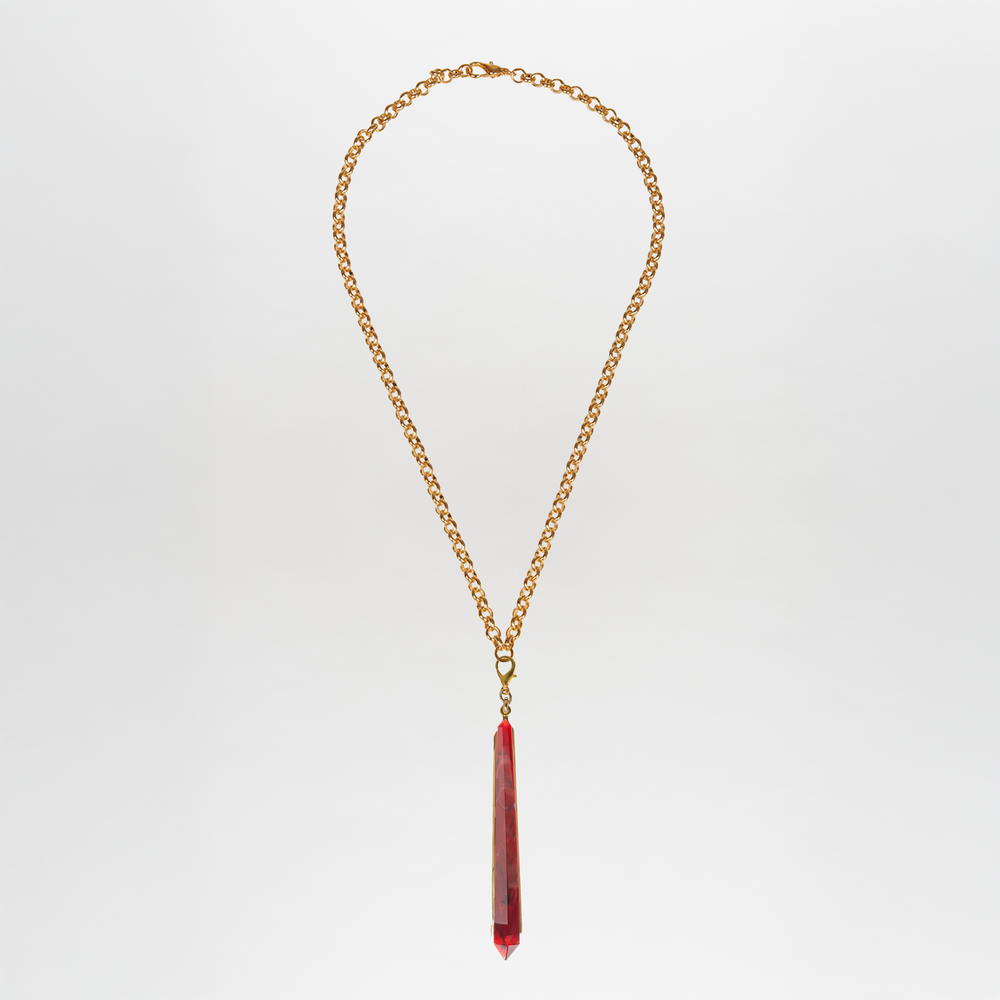 The Montse Necklace features a gold chain with a long, faceted Petralux® stone geometric pendant at the center, displayed against a plain white background.