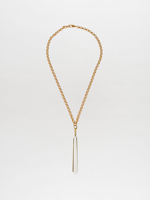 The Montse Necklace Pearl, a gold chain necklace with a long, pointed geometric crystal pendant on a white background, embodies the elegance of a Tcherassi design.