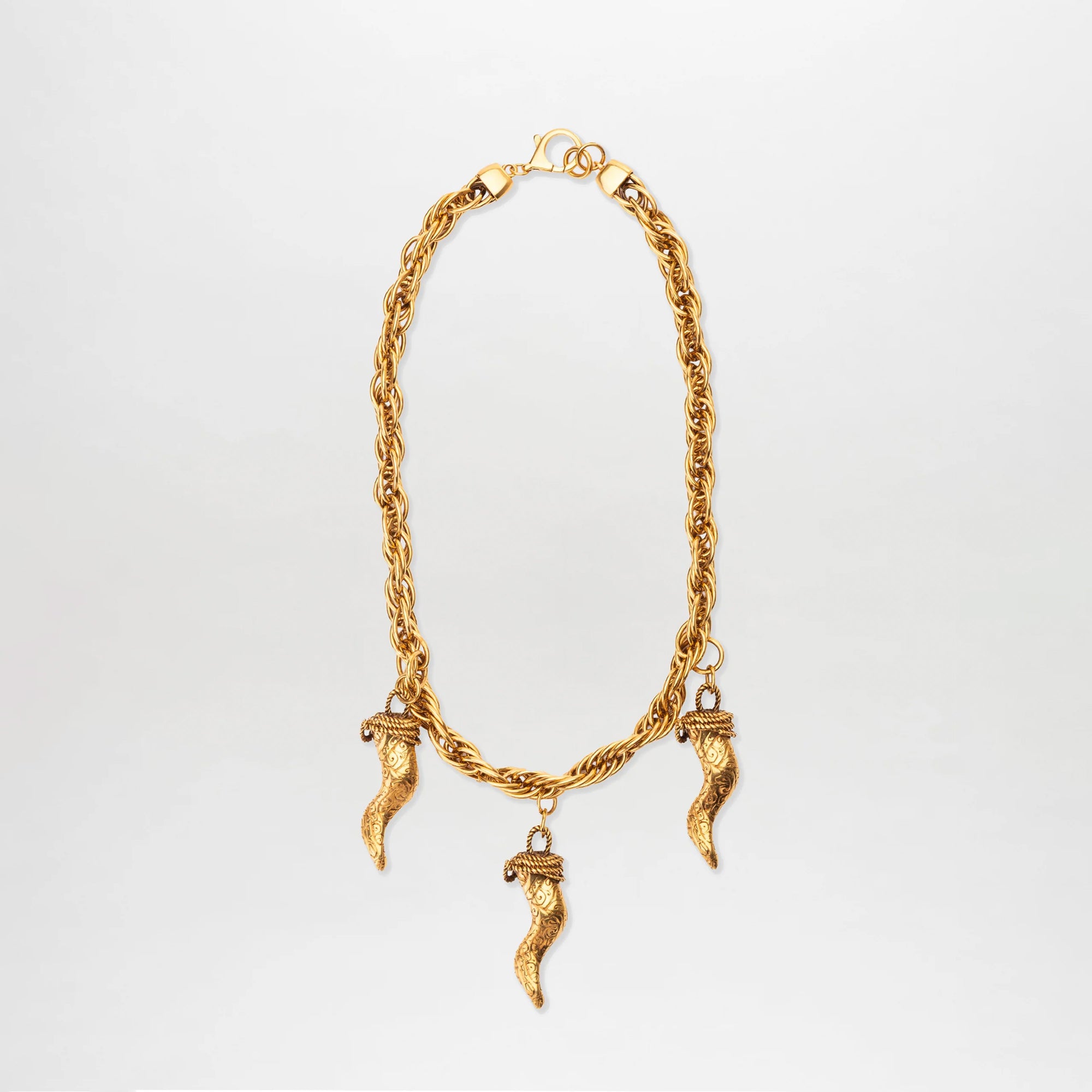 The Matilda Necklace is a gold-plated piece with three textured cornicello pendants, each capped with a decorative design, elegantly displayed against a plain white background.