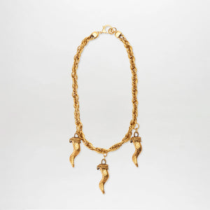 The Matilda Necklace is a gold-plated piece with three textured cornicello pendants, each capped with a decorative design, elegantly displayed against a plain white background.