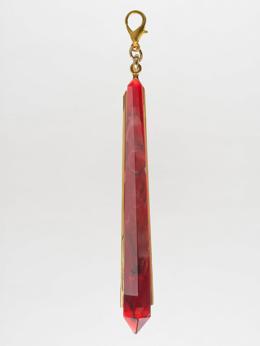 The Montse Necklace features a gold chain with a long, faceted Petralux® stone geometric pendant at the center, displayed against a plain white background.
