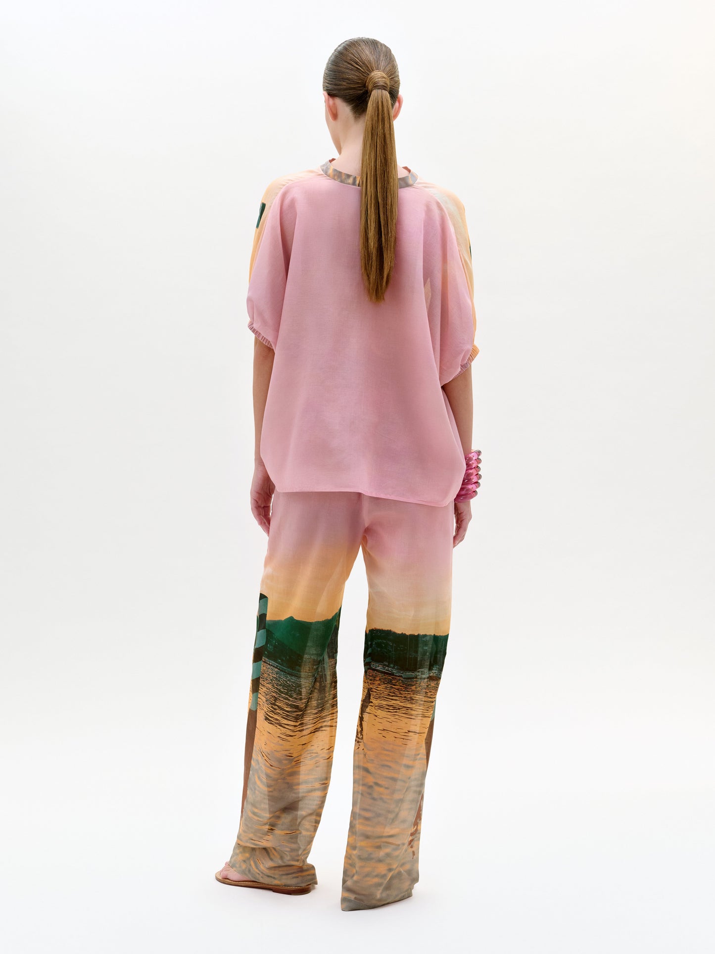 Person wearing a pink top and colorful gradient pants on a white background
