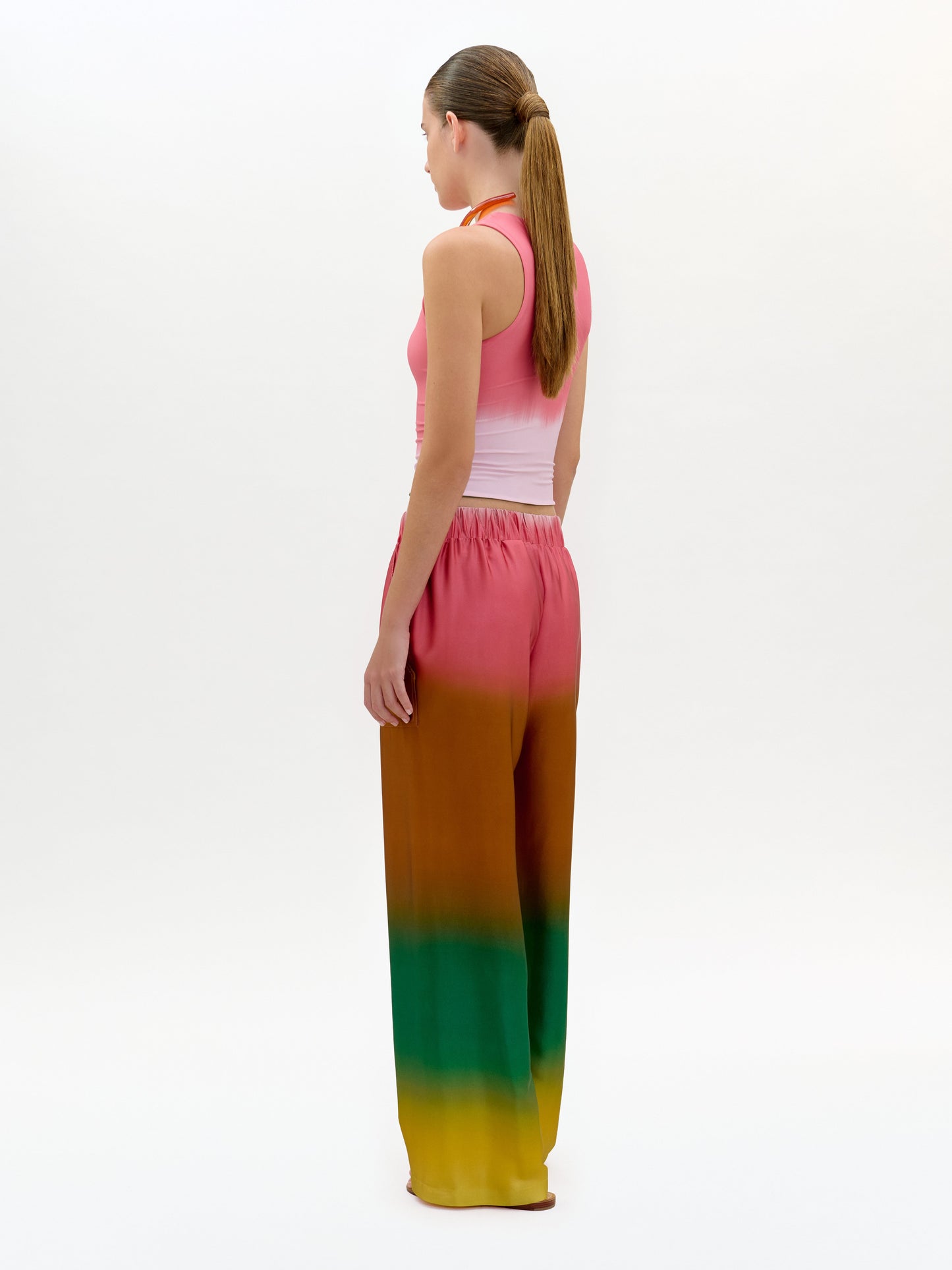 Woman wearing a colorful dress with a gradient from pink to green on a white background