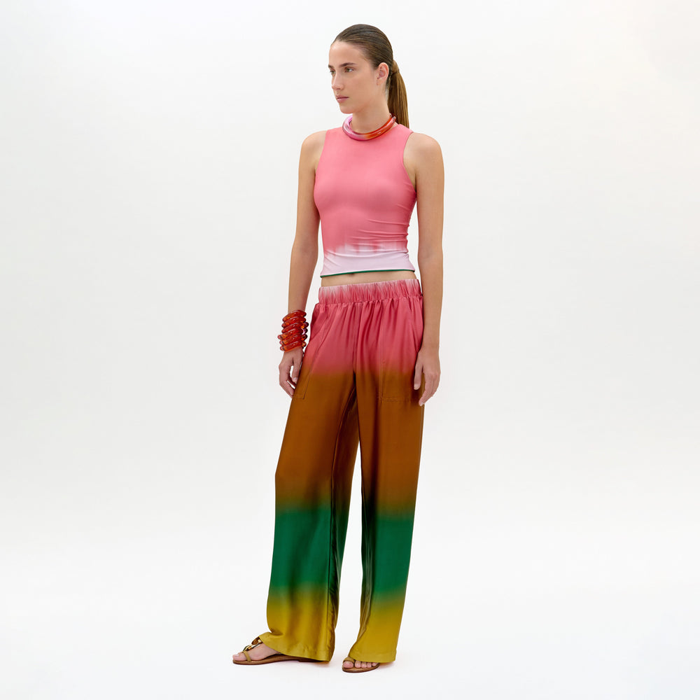 Woman wearing a pink sleeveless top and colorful gradient pants on a white background