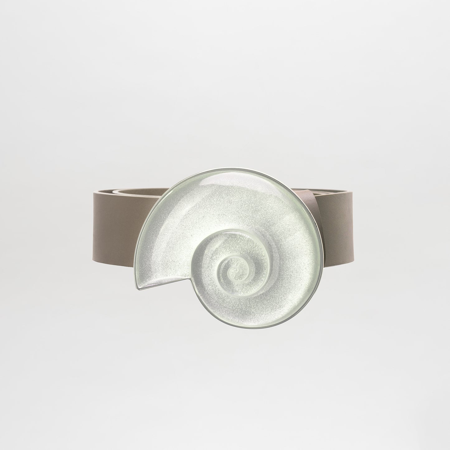 The Nautilus Belt features taupe Italian leather with a large spiral seashell-shaped silver buckle. Reminiscent of a fantasy stone design, it's made in Colombia and showcased against a plain white background.