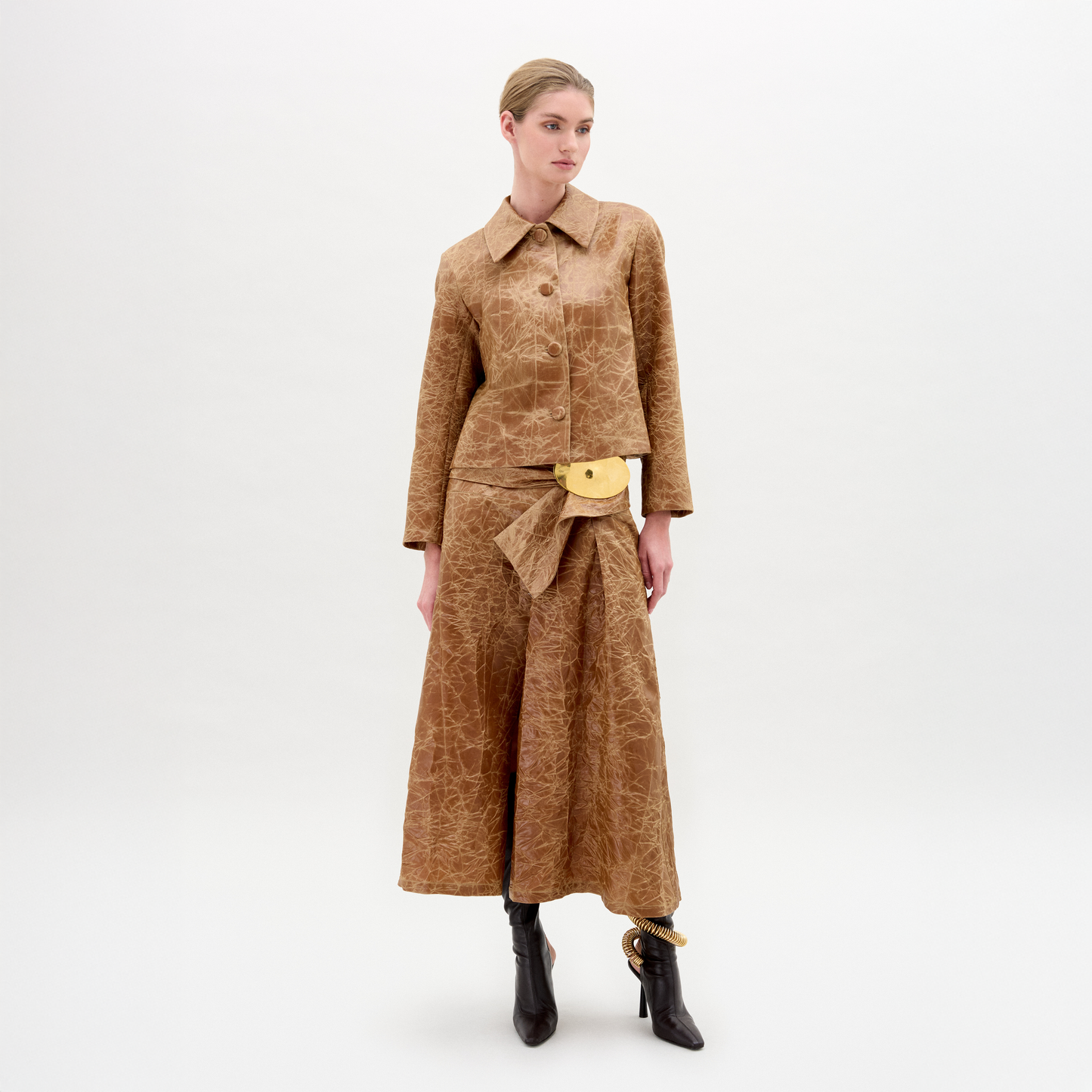 Woman wearing a brown textured outfit with a belt on a white background