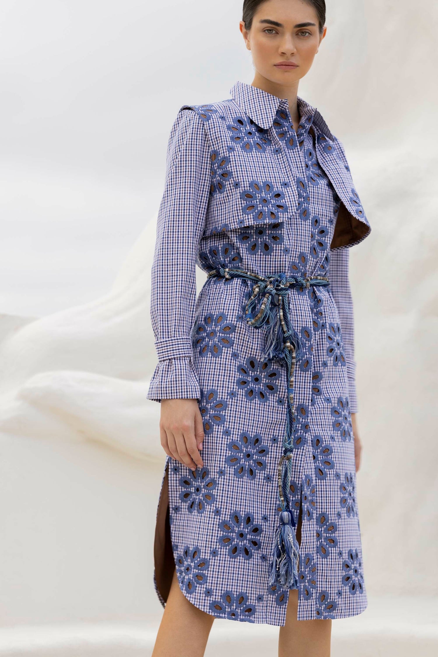 Person in a patterned long-sleeve dress with a rope belt standing against a light background.