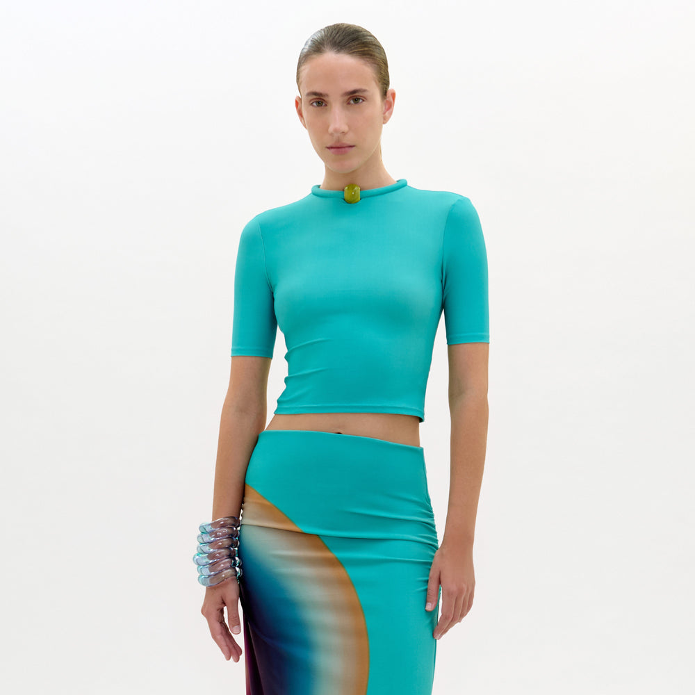 Woman wearing a teal outfit with a plain background