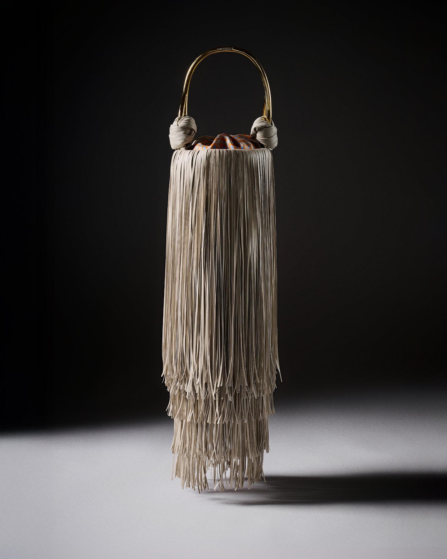 Decorative vase with layered fringe design on a dark background