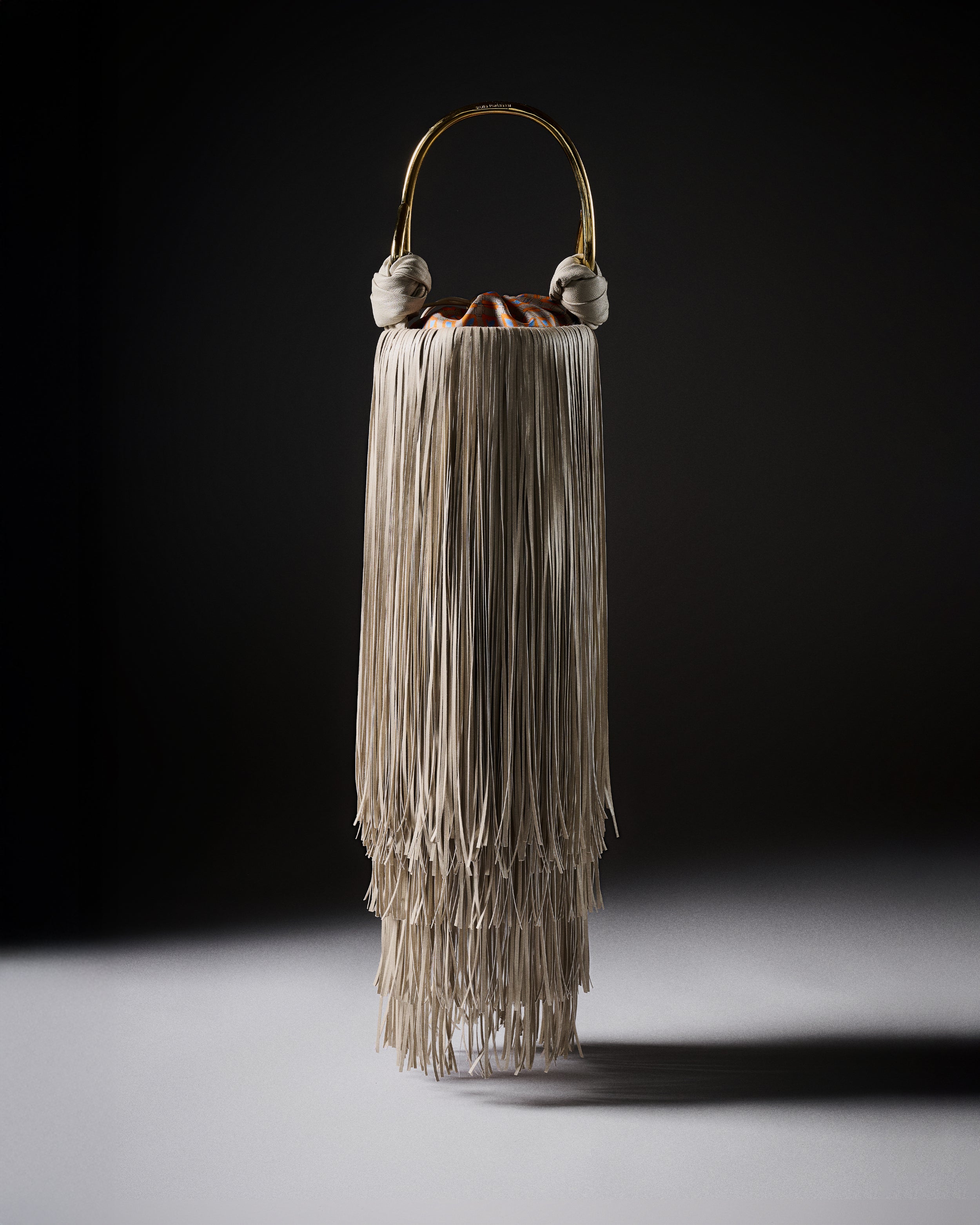 Decorative vase with layered fringe design on a dark background