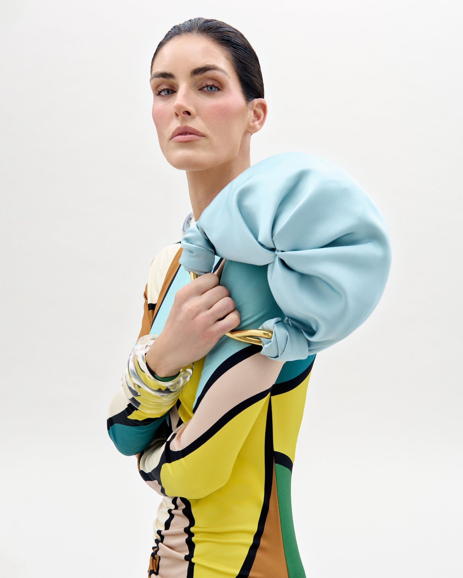 The supermdel Hillary Rhoda wearing a colorful outfit with a light blue jacket on a white background