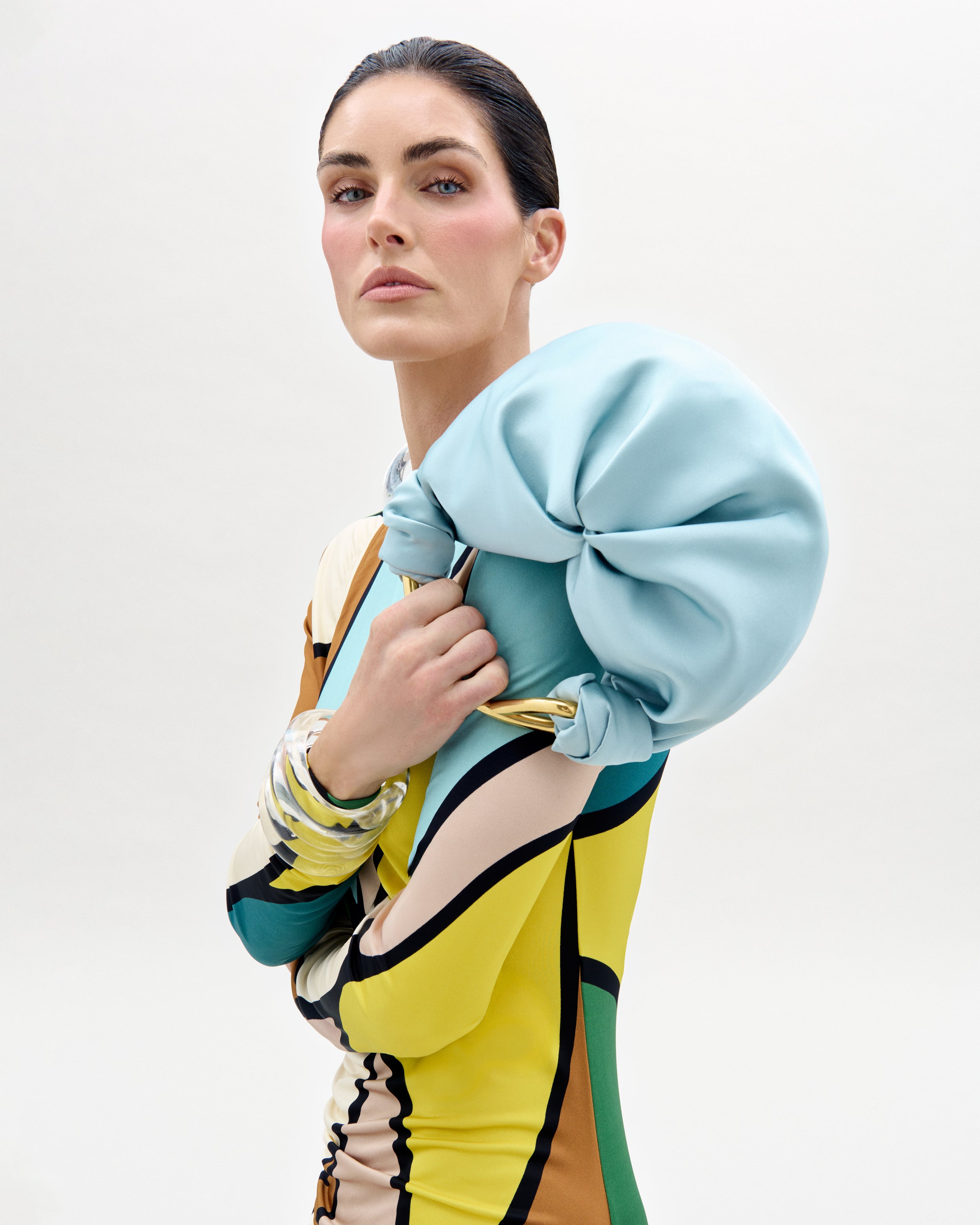 The supermdel Hillary Rhoda wearing a colorful outfit with a light blue jacket on a white background