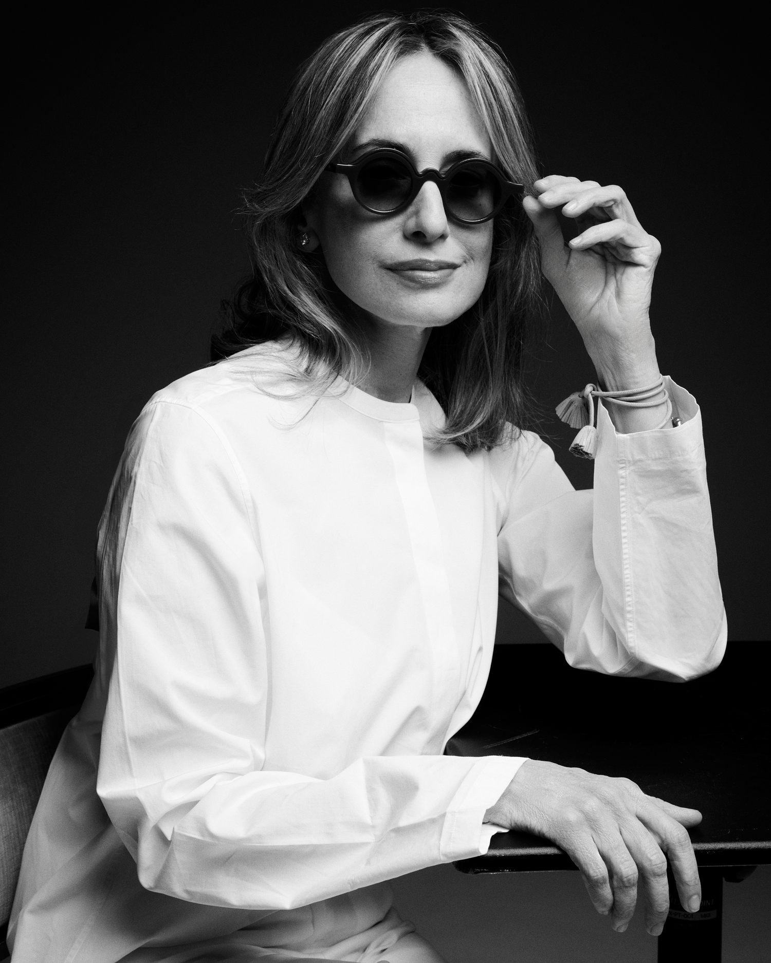 Black and white portrait of a woman wearing sunglasses and a white shirt.