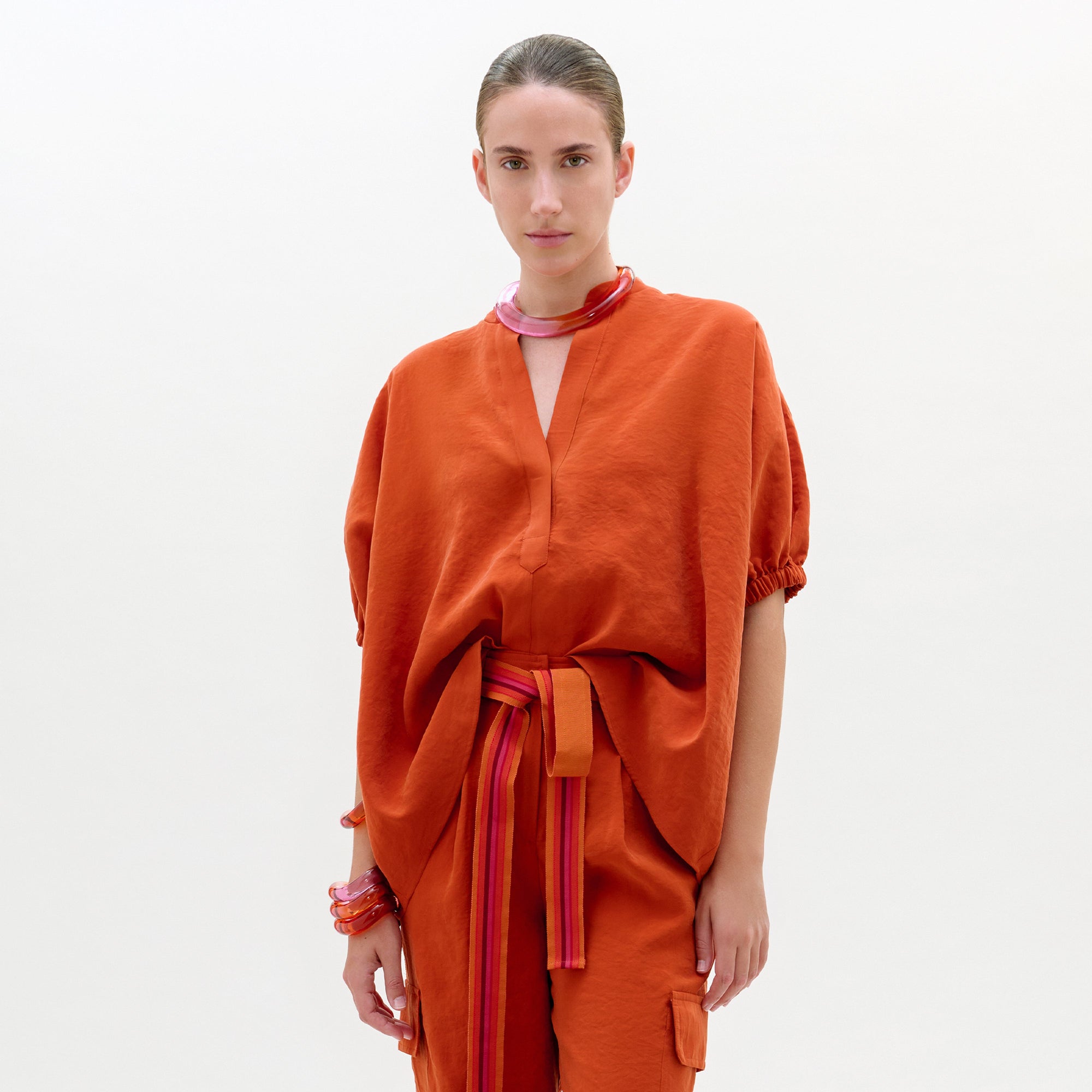 Woman wearing an orange outfit with a plain background