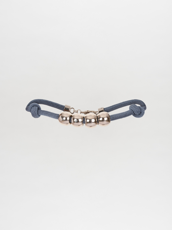 A Sam Belt Indigo with three silver metallic beads in the center, set against a white background. Pre-order now for shipping starting November 15, 2024.